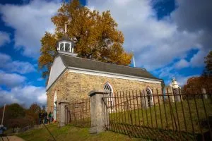 Sleepy Hollow's Old Dutch Church stands against a blue sky and dramatic clouds.