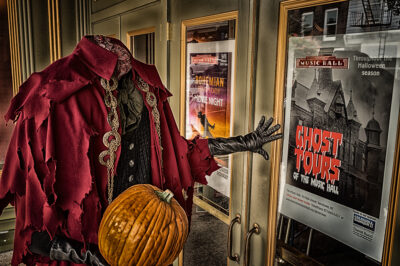 The headless horseman stands outside the Tarrytown Music Hall in front of a poster for the Hall's ghost tours.