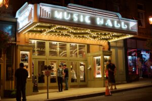 Patrons gather at night under the illuminated marquee of Tarrytown Music Hall.