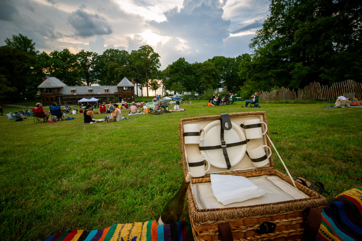 Picnickers on the lawn of Lyndhurst mansion enjoying live jazz music as the sun sets.