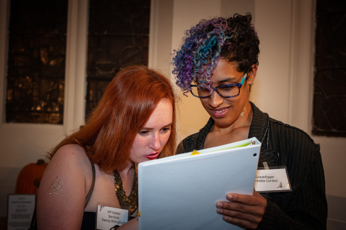 Two participants in Murder Mystery night at Sleepy Hollow Cemetery compare notes.