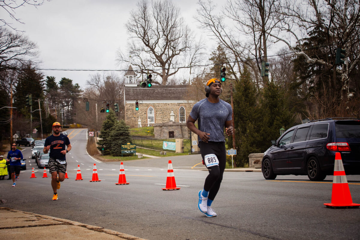 Runners participate in a half marathon in Sleepy Hollow, New York, with Old Dutch Church in background.