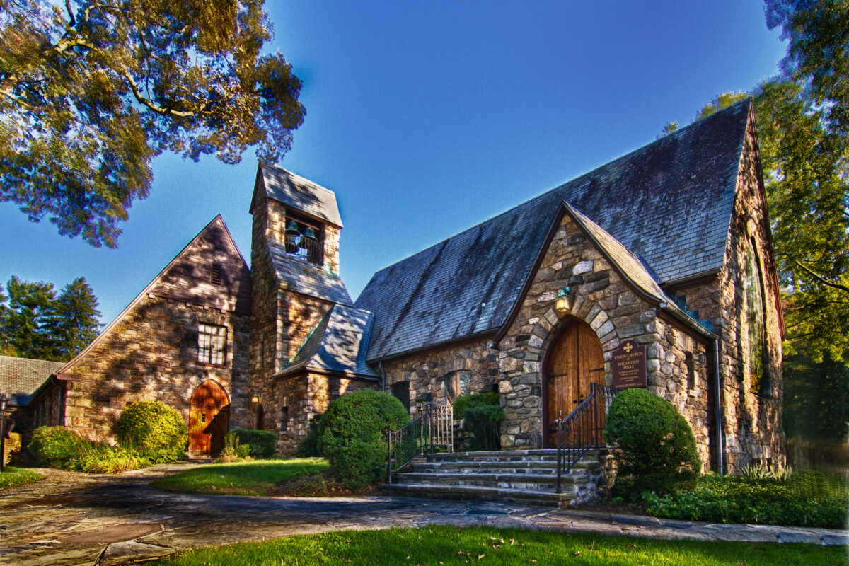 A view of the front entrance to Union Church of Pocantico Hills against a deep blue sky.