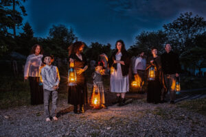A lantern-lit tour group in Sleepy Hollow Cemetery at dusk